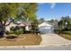 Charming single-story home with mature trees and a well-manicured front lawn and long driveway at 891 Lucky Ln, The Villages, FL 32162