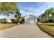 Single-story home with a well-manicured lawn, palm trees, and a two-car garage at 891 Lucky Ln, The Villages, FL 32162