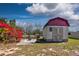 Backyard shed with red trim and a seating area in the yard with a firepit and flowering bush at 948 Dora Ave, Tavares, FL 32778