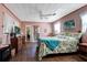 Relaxing bedroom with colorful bedspread, pink walls, ceiling fan, and attached bathroom view at 948 Dora Ave, Tavares, FL 32778