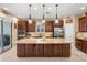 Well-lit kitchen with dark wood cabinets, stainless appliances, and a granite island at 1023 Timbervale Trl, Clermont, FL 34715