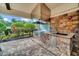 Outdoor kitchen featuring stone accents, stainless steel grill, sink, and ample counter space for outdoor dining at 1023 Timbervale Trl, Clermont, FL 34715