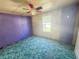Bedroom with purple accent wall and a multicolored ceiling fan at 103 Caroline Ave, Lady Lake, FL 32159