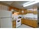 Well-lit kitchen with white appliances, light wood cabinets, and a double basin stainless steel sink at 10301 Us Highway 27 # 84, Clermont, FL 34711
