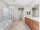 Bright bathroom featuring double sink vanity, bathtub, and glass enclosed shower at 11759 Se 91St Cir, Summerfield, FL 34491