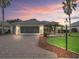 Charming single-story home with manicured lawn, mature palms, and brick driveway, captured during a beautiful sunset at 11759 Se 91St Cir, Summerfield, FL 34491