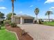 Attached garage and brick paver driveway, enhanced by palm trees and manicured landscaping at 11759 Se 91St Cir, Summerfield, FL 34491