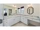 Bathroom featuring double sinks, large mirrors, elegant fixtures, and pristine white cabinetry providing both style and functionality at 1417 Forest Acres Dr, The Villages, FL 32162