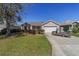 Charming home with a well-kept lawn, landscaping, and a vintage golf cart parked in the driveway at 1417 Forest Acres Dr, The Villages, FL 32162