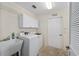 Well-equipped laundry room with white cabinets, modern washer and dryer, and a utility sink at 1417 Forest Acres Dr, The Villages, FL 32162