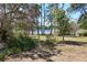 Charming backyard garden featuring mature trees and a view of the tranquil lake, perfect for relaxing at 17108 Pine Ridge Dr, Umatilla, FL 32784