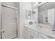 Modern bathroom features a glass-enclosed shower, double sink vanity with stone counters, and decorative blue accents at 1773 Hallandale Ln, The Villages, FL 32162