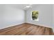 Inviting bedroom with neutral walls, fan, wood-look floors, and a window offering a view of a vibrant tree at 1773 Hallandale Ln, The Villages, FL 32162
