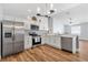 Well-lit kitchen with stainless steel appliances, white cabinets, and wood-look floors, ideal for cooking and entertaining at 1773 Hallandale Ln, The Villages, FL 32162
