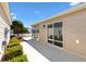 Back patio featuring sliding glass door and an overhang, surrounded by lush landscaping at 1773 Hallandale Ln, The Villages, FL 32162