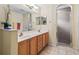 Bathroom features a double vanity and a glass-enclosed shower, complete with warm wood cabinetry at 17883 Se 125Th Cir, Summerfield, FL 34491
