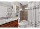 Bathroom with marble countertop, white shower curtain, and cherry wood vanity at 2213 Evans Prairie Trl, The Villages, FL 32163