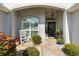 Inviting front porch with a rocking chair, potted plants, and a wreath on the front door at 2213 Evans Prairie Trl, The Villages, FL 32163