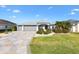 Charming home featuring a well-manicured lawn, mature landscaping, a stone driveway, and a three-car garage at 2213 Evans Prairie Trl, The Villages, FL 32163