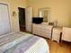 Bedroom features a dresser with mirror, bedside table, and a doorway leading to another room at 2569 Errol Ter, The Villages, FL 32162