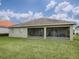 A backyard featuring a well-kept lawn and a covered patio with sliding glass doors leading inside at 30454 Island Club Dr, Deer Island, FL 32778