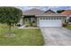Charming single-story home featuring a well-manicured lawn, a green door, and an attached two-car garage at 30454 Island Club Dr, Deer Island, FL 32778