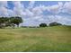 Scenic view of the meticulously maintained golf course with lush green fairways and mature trees, all under a beautiful sky at 30454 Island Club Dr, Deer Island, FL 32778