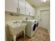 Well-lit laundry room with white cabinets, utility sink, and a washer and dryer at 30454 Island Club Dr, Deer Island, FL 32778