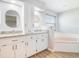 Bathroom with dual sinks, granite countertops, white cabinetry, a bathtub, and a separate toilet room at 6410 Tildon Ct, Leesburg, FL 34748
