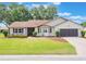 Charming single-story home featuring a well-manicured lawn, brick driveway, and an attached two-car garage at 6410 Tildon Ct, Leesburg, FL 34748