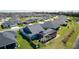 Aerial shot of blue home with screened in lanai with pool, lush landscaping, and a picturesque neighborhood with pond views at 6444 Mcknight Loop, The Villages, FL 34762