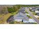 Back aerial view of home showing screened in lanai with pool, well-manicured yard, and neighborhood with mature trees at 6444 Mcknight Loop, The Villages, FL 34762