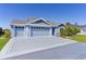 Exterior elevation with large driveway, well-kept lawn and landscaping and a two car garage at 6444 Mcknight Loop, The Villages, FL 34762
