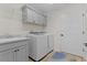 Functional laundry room with modern appliances, storage cabinets, and a utility sink at 6444 Mcknight Loop, The Villages, FL 34762