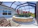 A covered pool with a stacked stone surround is enhanced by colorful potted plants and tropical decor at 6444 Mcknight Loop, The Villages, FL 34762