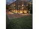 An exterior view of the screened-in pool area at night with landscape lighting at 6444 Mcknight Loop, The Villages, FL 34762