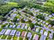 From above, a picturesque community featuring various homes around a pond, with a highlighted property nestled among lush trees at 701 Cottage Park Ln, Leesburg, FL 34748