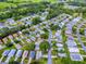From above, a tranquil community with mature landscaping and winding streets surrounds a home, near a golf course at 701 Cottage Park Ln, Leesburg, FL 34748
