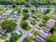 An aerial shot features a charming community with a highlighted property, boasting green lawns and mature trees at 701 Cottage Park Ln, Leesburg, FL 34748