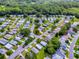 A scenic aerial view captures a quiet residential area, featuring a cozy home highlighted amidst mature trees and winding roads at 701 Cottage Park Ln, Leesburg, FL 34748