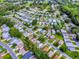 An aerial view of a charming neighborhood with well-maintained lawns, mature trees, and a golf course in the distance at 701 Cottage Park Ln, Leesburg, FL 34748