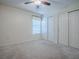 Bright bedroom featuring neutral carpet, ceiling fan, window with blinds, and closet with sliding doors at 701 Cottage Park Ln, Leesburg, FL 34748