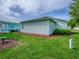 View of back of home with light siding and grass yard with landscaped flower beds and cloudy sky at 701 Cottage Park Ln, Leesburg, FL 34748