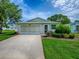 Charming home with a manicured lawn, attached garage, and inviting entrance under a bright blue sky at 701 Cottage Park Ln, Leesburg, FL 34748