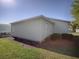 Exterior view of home with light siding, green grass, and minimal landscaping at 701 Cottage Park Ln, Leesburg, FL 34748