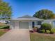 Charming single-story home featuring a well-kept lawn, manicured bushes, and attached garage at 701 Cottage Park Ln, Leesburg, FL 34748