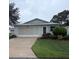 Charming home with attached garage, mature landscaping, and driveway leading up to the garage at 701 Cottage Park Ln, Leesburg, FL 34748