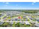 Community aerial featuring a home with lake views and a backdrop of lush trees and clear blue skies at 7250 Trundle Ter, The Villages, FL 34762