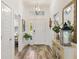 Bright foyer featuring wood-look floors, decorative light fixture and white front door at 7250 Trundle Ter, The Villages, FL 34762