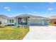 Charming home featuring a landscaped lawn, neutral paint, three car garage, and covered porch at 7250 Trundle Ter, The Villages, FL 34762